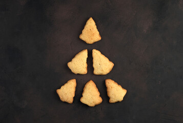 Cookies are laid out in the shape of a Christmas tree on a brown concrete background. The concept of New year and Christmas.