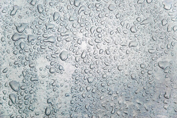 small and large drops of condensation on frosted colored glass
