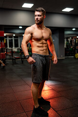 Fototapeta na wymiar Handsome man with big muscles, posing at the camera in the gym. Full length portrait.