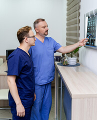 Obraz premium Doctors are examining x-ray of a patient. Male radiologists standing near enlighted board. Medical office background.