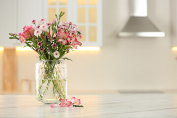Vase with beautiful flowers on table in kitchen, space for text. Stylish element of interior design