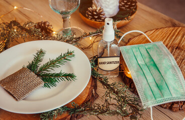 Christmas eve holiday party decorated table set with disposable medical mask and alcohol hand...