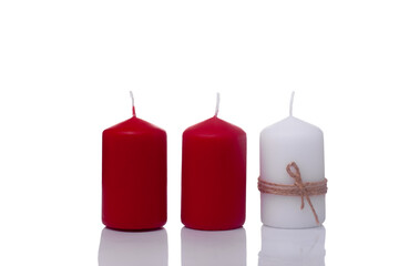two red candles and one white candle in a jute rope, isolated on a white background.