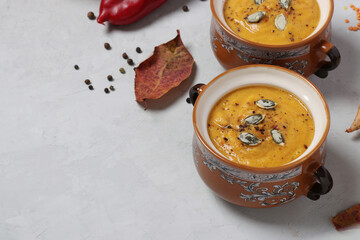 Vegetarian autumn creamy pumpkin soup with red lentils on gray background, copy space. Horizontal format