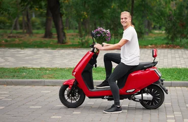 Foto op Plexiglas Full length shot of smiling delivery guy riding on red  scooter with bouquet of flowers. Romantic date and surprise concept © oes