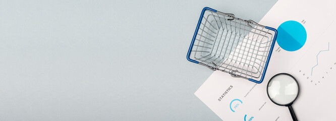 empty shopping basket and magnifier on blue background with marketing statistics, banner with copy...