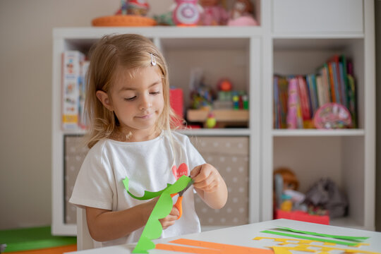 Little girl cutting paper, home education, practice scissors skills.