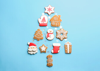 Delicious gingerbread cookies arranged in shape of Christmas tree on light blue background, flat lay