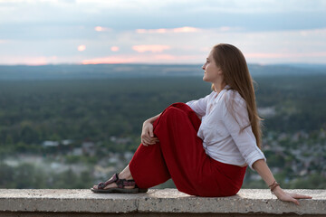 Girl is resting while sitting on observation deck. Young woman travels alone