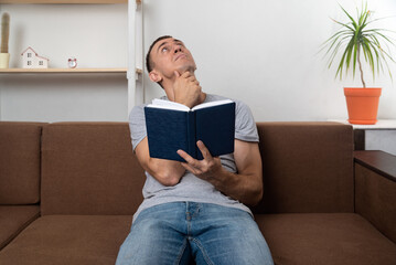 Obraz premium Man reads the Bible and looks up thoughtfully. Search for God