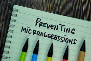 Preventing Microaggressions write on a book isolated on Wooden Table.