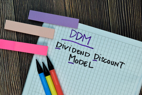 DDM - Dividend Discount Model write on a book isolated on Wooden Table.