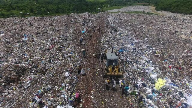 Truck pushes garbage at Duquese landfill and people collect garbage. Aerial