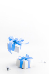 Fototapeta premium Christmas sale. White gift box with blue ribbon, New Year balls in xmas composition on white background for greeting card. Christmas, winter, new year concept.