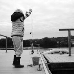 Young boy catching crabs on a pontoon in monochrome.