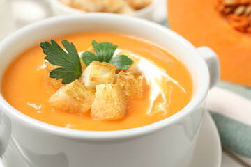 Delicious pumpkin soup in bowl on table, closeup