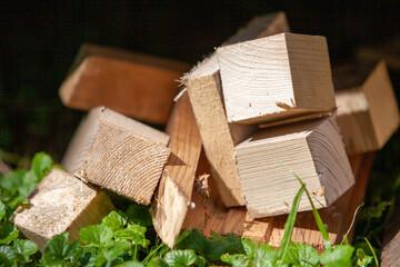 Wooden blocks of rectangular and square shape left on the grass after the construction of the house.