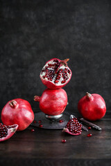 Still life with ripe juicy pomegranates on a wooden table. Dark photo.