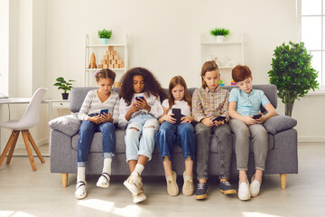 Group of multiethnic kids playing online games on mobile phones and ignoring real life - obrazy, fototapety, plakaty