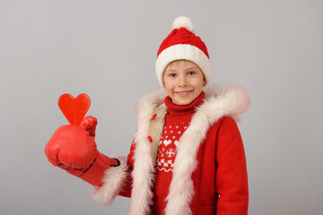 A boy dressed as Santa Claus is holding a heart with a boxing glove.