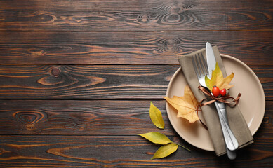 Festive table setting with autumn leaves and space for text on wooden background, flat lay. Thanksgiving Day celebration