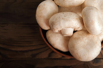 Mushrooms in a plate on a dark wooden board. Champignons and knife close up and copy space.