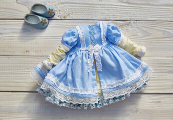 Beautiful vintage dress for a doll on a white wooden background
