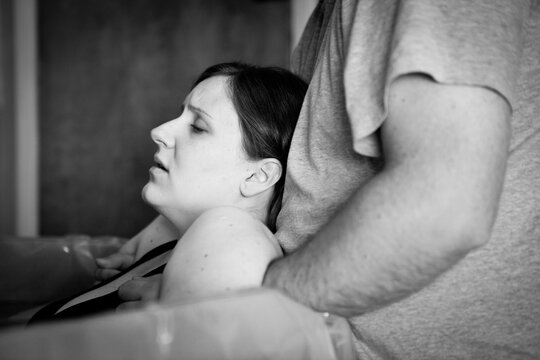 Woman in Labor in Birthing Pool Being Comforted by Husband During at Home Birth