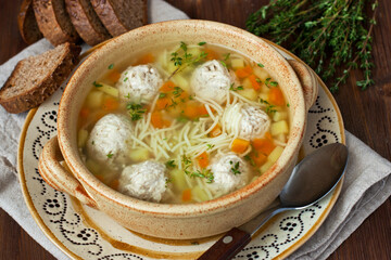 Chicken  soup with meatballs  in bowl  on wooden surface, rustic style