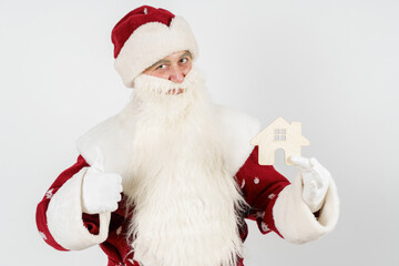 Santa Claus keeps as a gift - a house. Isolated on light background