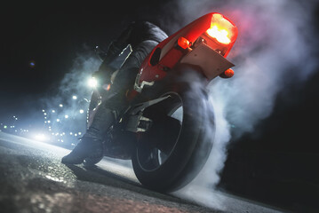 Motorbiker is burning a tire rubber on night road.