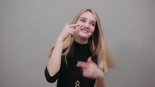 Pointing fingers at cheeks. Cheerful posing with finger on cheek. Health, beauty concept smiling young. Face of beautiful aiming. Cute funny showing puffed. Young attractive woman, dressed sweater