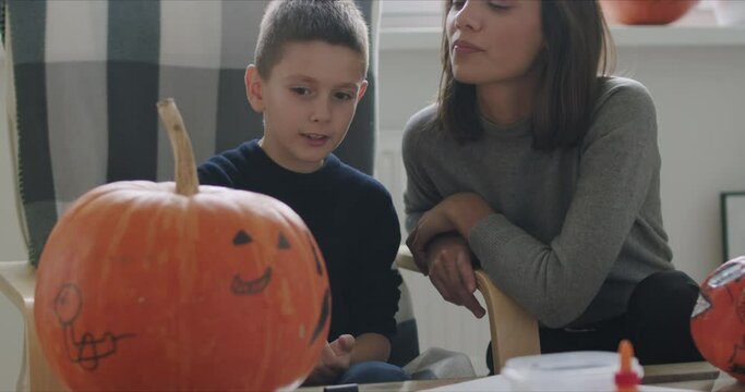 Woman with son paint pumpkin for Halloween