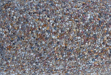 texture of stones in a light-colored concrete fence, crushed stone