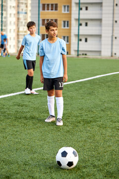 sportive child boy in uniform kicking ball, they have penalty in this round. kids play football, competition in stadium, in field