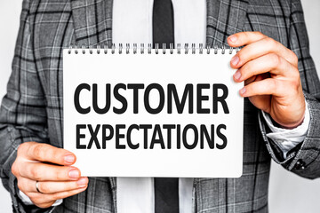 business, technology, internet and networking concept - businessman in gray fashionable business suit holding a white notebook with conference inscription CUSTOMER EXPECTATIONS inscription