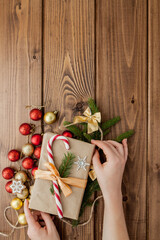 Woman s hands wrapping Christmas gift, close up. Unprepared christmas presents on wooden background with decor elements and items, top view. Christmas or New year DIY packing Concept.
