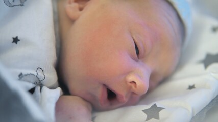 Adorable newborn baby sleeping peacefully in his crib in the hospital room . High quality photo