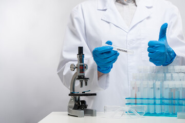 Scientist in blue protection gloves analyzing covid-19 vaccine with microscope on laboratory room background. Healthcare and medical concept.