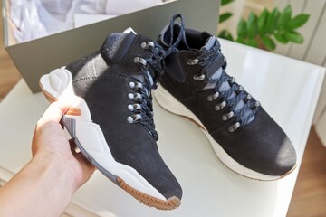 New leather black waterproof hiking winter autumn boots in hands of female