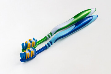 Two new toothbrushes, green and blue on a light background
