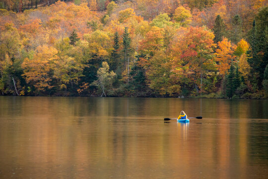 Woman in a blue kayak on a lake in the fall in New England