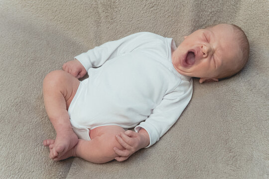 Cute newborn baby yawning and stretching on the blanket. High quality photo