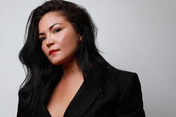 Portrait of attractive latin woman with long hair, posing over white background wall. Space for text.