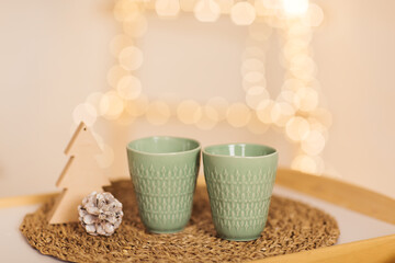Home interior. A bed with a white knitted blanket. Breakfast table-tray with two cups on the bed. Elements of the Christmas holiday. Close-up