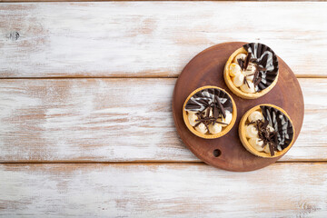 Fototapeta na wymiar Sweet tartlets with chocolate and cheese cream on a white wooden background. flat lay, copy space.