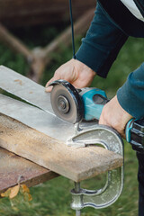 Close up worker cutting metal with angle grinder. Man work in outdoor workshop.