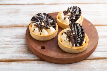 Sweet tartlets with chocolate and cheese cream on a white wooden background. side view. - obrazy, fototapety, plakaty