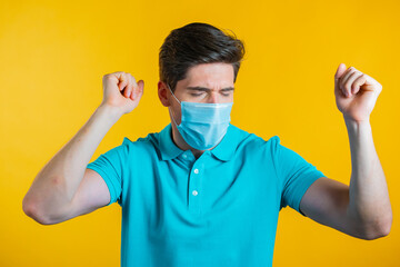 Man in medical mask dancing positive on yellow studio background. Handsome male model guy. Party, happiness, freedom, youth concept.