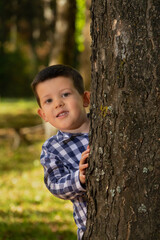 Boy peeks out from behind the tree.